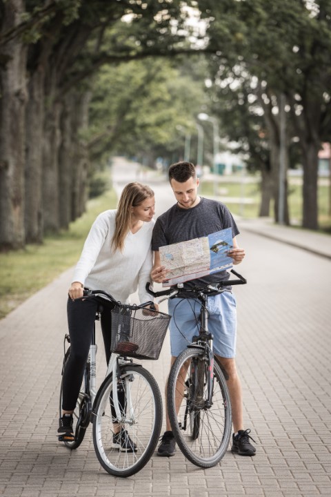 Divi jaunieši skatās tūrisma karti uz velosipēdiem